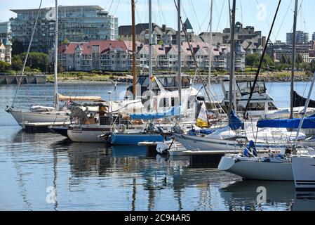 Barche a vela e barche a motore sono ormeggiate lungo le banchine a Fisherman’s Wharf a Victoria, British Columbia, Canada, sull'isola di Vancouver. In background sono Foto Stock