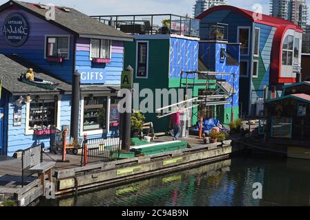 Un operaio porta una scala accanto a un negozio di articoli da regalo galleggiante e galleggianti al Fisherman's Wharf di Victoria, British Columbia, Canada, sull'isola di Vancouver. Fi Foto Stock