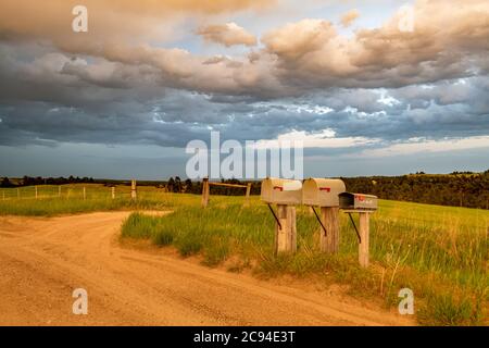 Immagine di una classica strada sterrata nel Midwest con una prospettiva della strada che porta al nulla e caselle postali accanto a sidirade. Foto Stock