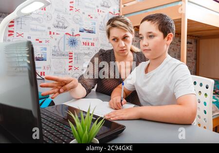 La mamma tiene un computer portatile e mostra la mano al figlio sullo schermo. Scolarizzazione Foto Stock