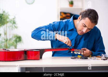 Giovane uomo riparatore riparando la chitarra Foto Stock