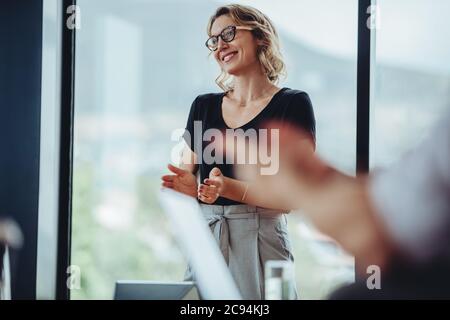 Donna professionista che batte le mani dopo una conferenza di successo in ufficio. Gli uomini d'affari si aggrappano dopo la presentazione nella sala riunioni. Foto Stock