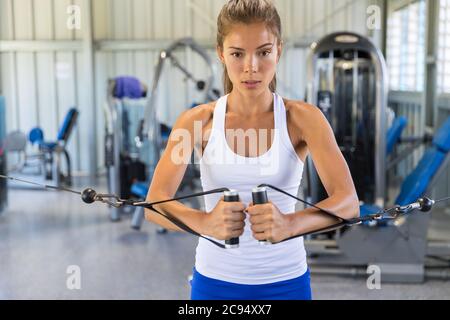 Fitness donna allenarsi in palestra con torre di cavi. Fit Asian ragazza formazione toned braccia e corpo Foto Stock