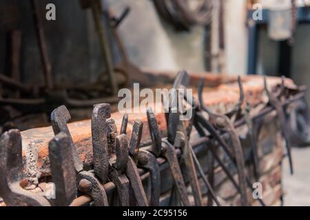 Vecchie pinze storiche e pinze di fabbro appese su fucina arrugginita di fronte al camino Foto Stock