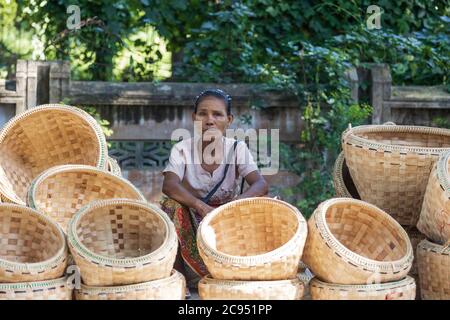 Sagaing/Myanmar-3 ottobre 2019: Un venditore birmano donna sta vendendo cestini di vimini fatti di bambù. Foto Stock