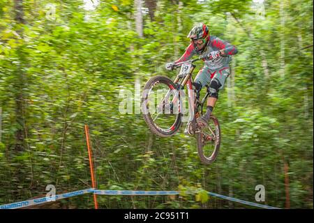 Un concorrente maschile di livello mondiale è in volo ai Campionati Mondiali di Mountain bike Downhill 2016 dell'UCI che si tengono a Cairns, Australia. Foto Stock