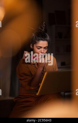 Giovane artista focalizzato utilizzando il laptop in un laboratorio d'arte. Opere d'arte moderne dipingono su tela, opere d'arte creative, contemporanee e di successo Foto Stock