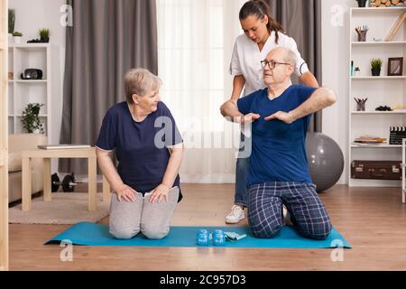 Assistenza facendo fisioterapia a casa con persone anziane. Assistenza domiciliare, fisioterapia, stile di vita sano per anziani, formazione e recupero con medico professionale. Foto Stock