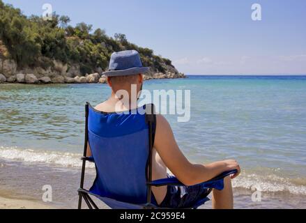 Giovane uomo in cappello rosso che guarda al mare Foto Stock