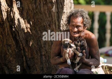 Sagaing/Myanmar-3 ottobre 2019: Un vecchio birmano porta con sé due cuccioli con amore. Foto Stock