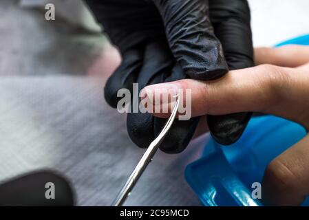 Il processo di creazione di una manicure. Primo piano di una donna in un salone. Estetista mette unghie su un cliente. Foto Stock