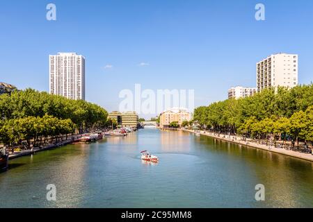 Le persone che si godono un tour a bordo di una barca elettrica a noleggio sul bacino della Villette a Parigi, in Francia, con i due ex magazzini in background. Foto Stock