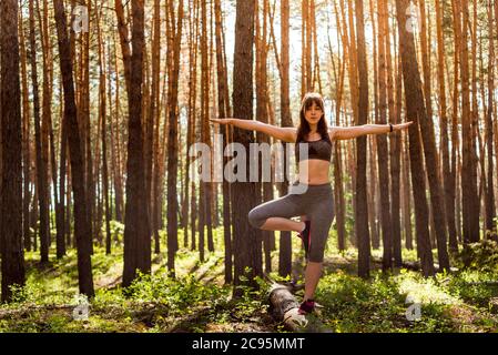 Yoga nella foresta estiva del mattino, all'aperto con l'effetto della luce. Donna Yoga. Il concetto di uno stile di vita sano e relax. Foto Stock