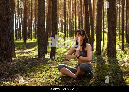 Yoga nella foresta estiva del mattino, all'aperto con l'effetto della luce. Donna Yoga. Il concetto di uno stile di vita sano e relax. Foto Stock