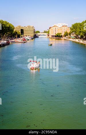 Le persone che si godono un tour a bordo di una barca elettrica a noleggio sul bacino della Villette a Parigi, in Francia, con i due ex magazzini in background. Foto Stock