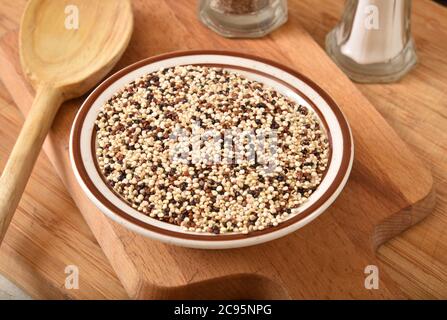 Una ciotola di quinoa tricolore su un tagliere Foto Stock