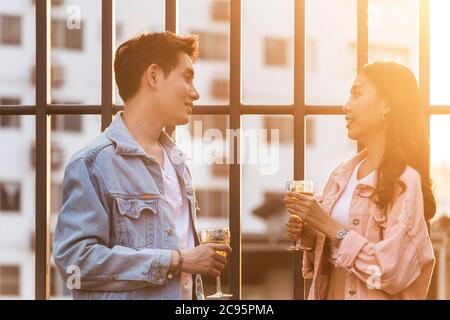 coppia amante asiatica uomo e donna che brinda e brinda con bicchieri di vino bianco per celebrare la prima datazione in festa a cena in estate. Foto Stock