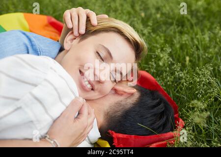 Primo piano di due donne felici che giacciono sull'erba verde e abbracciano si amano Foto Stock
