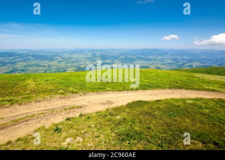 strada montana attraverso prati erbosi. meravigliosa avventura estiva. nuvole sul cielo blu Foto Stock