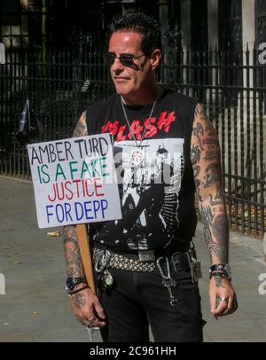Un fan di Johnny Depp attende fuori dall'High Court di Londra con un cartello che chiama Amber ha sentito un falso. Johnny Depp sta citando il giornale Sun per i libel Foto Stock