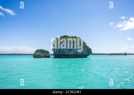 Bella stagione di UPI Bay, Pines Island, nuova caledonia: Laguna turchese, rocce tipiche, vegetazione lussureggiante, cielo blu Foto Stock