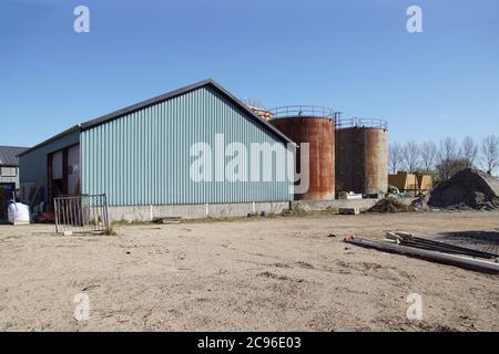 Vecchi silos arrugginiti, un capannone verde e un mucchio di sabbia. Alkmaar, Paesi Bassi, marzo Foto Stock