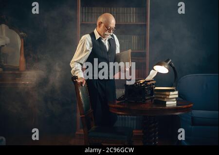 Lo scrittore anziano lavora su una macchina da scrivere d'epoca Foto Stock