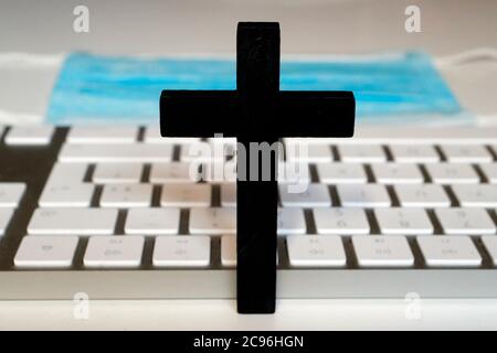 Epidemia di coronavirus (COVID-19). Croce cristiana, laptop e maschera chirurgica. Francia. Foto Stock