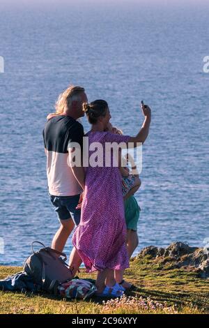 Una famiglia in vacanza staycation divertirsi scattando una foto selfie in piedi su Pentire Point East a Newquay in Cornovaglia. Foto Stock