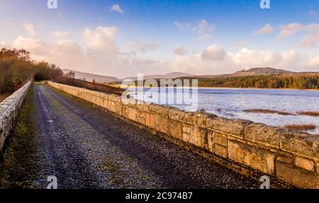 Il vecchio Viadotto Stroan a Loch Sroan al tramonto in inverno, sulle acque nere di Dee Foto Stock