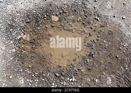 La struttura di sfondo dell'asfalto danneggiato causa un poolo su una superficie stradale che ha bisogno di una foto di stock di riparazione su strada Foto Stock