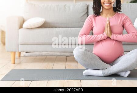 Attesa donna nera in posizione di loto che fa yoga a casa Foto Stock