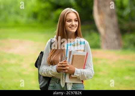 Ritratto all'aperto di una bellissima ragazza studentesca con libri da lavoro e zaino al campus Foto Stock