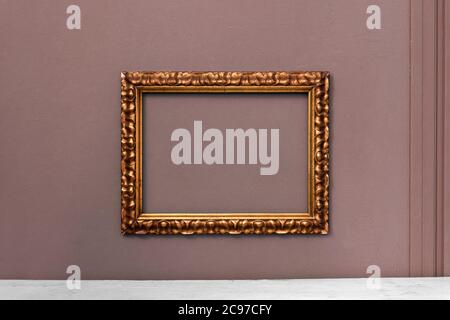 Cornice ornata in legno d'oro vintage appesa su una parete interna pronta per la vostra opera d'arte o pittura in un arredamento di interni concetto Foto Stock