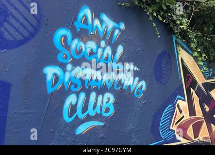 Graffiti topici spruzzati su un muro di graffiti a Swansea, Regno Unito, dicendo "Anti Social Distancing Club". Foto Stock