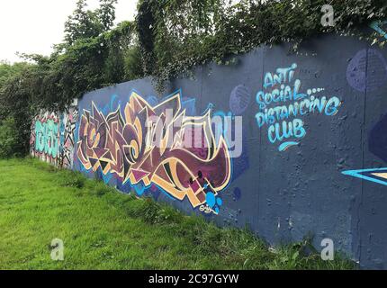 Graffiti topici spruzzati su un muro di graffiti a Swansea, Regno Unito, dicendo "Anti Social Distancing Club". Foto Stock