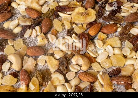 Mescolare le noci e la frutta secca su uno sfondo grigio pietra. Arachidi, ananas canditi, uvetta, banane secche, fichi, mandorle. Foto Stock