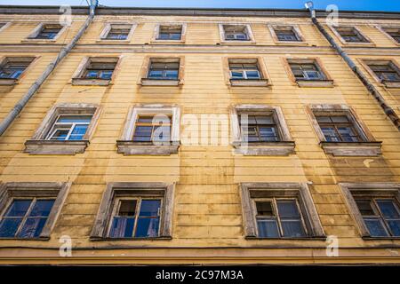 Vecchie finestre in una storica casa gialla in uno dei cortili centrali di San Pietroburgo, Russia. Foto Stock