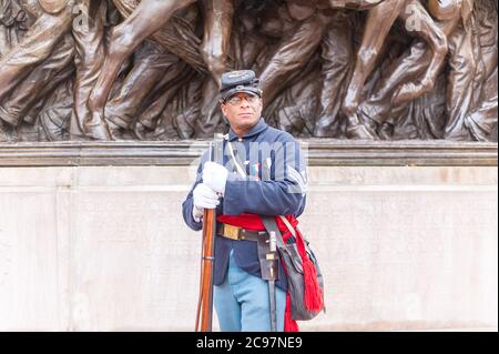 Membro del 54° gruppo di reenattori regimentali del Massachusetts che si pone di fronte al monumento in bronzo ad alto rilievo di Augustus Saint-Gauden sul Boston Common t. Foto Stock