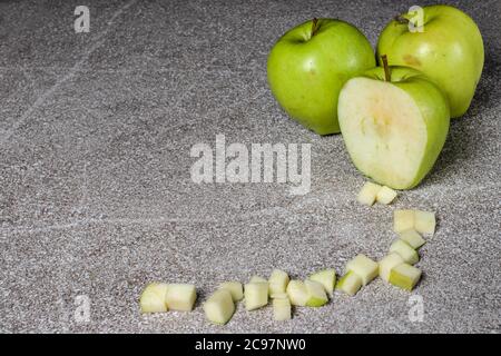 Mele verdi succose dorate su sfondo grigio. Mele a cubetti. Foto Stock