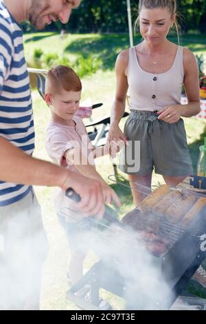 Famiglia con un barbecue nel cortile Foto Stock