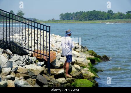 Bethany Beach, Delaware, U.S.A - 20 luglio 2020 - un uomo che pesca vicino alle rocce sulla baia Foto Stock