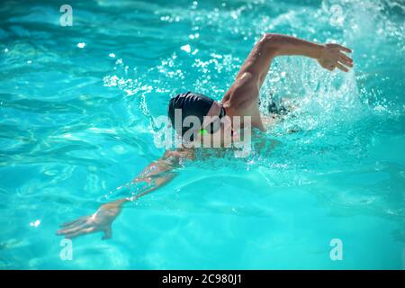 Uomo che nuota sul suo fianco in piscina Foto Stock
