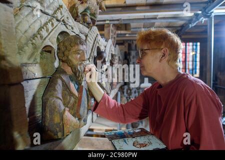 Halberstadt, Germania. 09 luglio 2020. Martina Runge, restauratrice di sculture medievali, opera nella cattedrale su ponteggi con un pennello su una figura apostola della croce trionfale. Non applica nuova vernice, ma la cosiddetta 'acqua-Sporca' (acqua sporca), che agisce sulla vernice rimanente. La croce trionfale in legno sul rood screen della chiesa è stata restaurata negli ultimi mesi. La croce dell'anno 1220 mostra la scena della crocifissione sul Golgota. Credit: Klaus-Dietmar Gabbert/dpa-Zentralbild/ZB/dpa/Alamy Live News Foto Stock