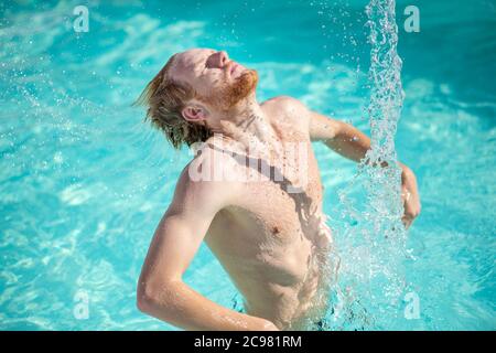 Uomo con occhi chiusi che spruzzi d'acqua in piscina Foto Stock