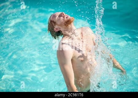 Uomo in piedi sotto acqua spruzzata in piscina Foto Stock