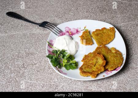 Frittelle di patate su un piatto, servite con panna acida e prezzemolo. Foto Stock