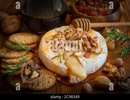 Tavola di formaggio servita per un antipasto: brie al forno, cracker, marmellata e noci. Foto Stock