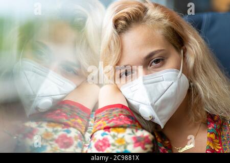 Una ragazza bionda che indossa una maschera si siede in una carrozza del treno sulla ferrovia sud-occidentale, Inghilterra, 26 luglio 2020 Foto Stock