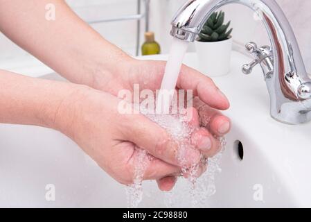 Uomo che lava le mani, mani ravvicinate dell'uomo in bagno con sapone e flusso d'acqua, immagine concettuale sull'igiene Foto Stock
